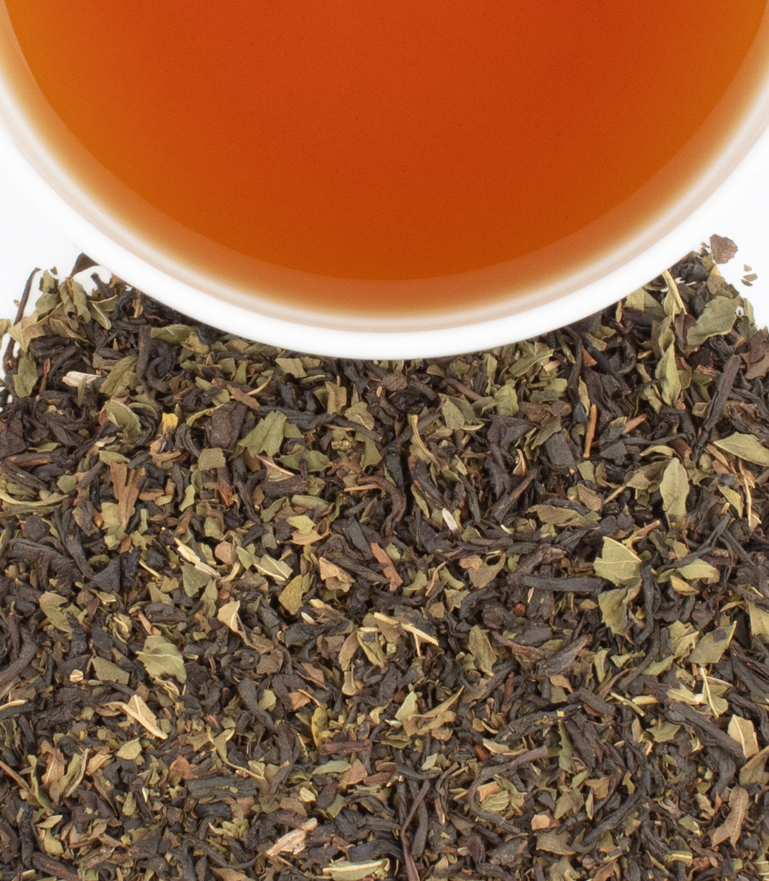 Bag of 50 Chocolate Mint tea sachets with brewed tea in a cup above loose tea leaves.