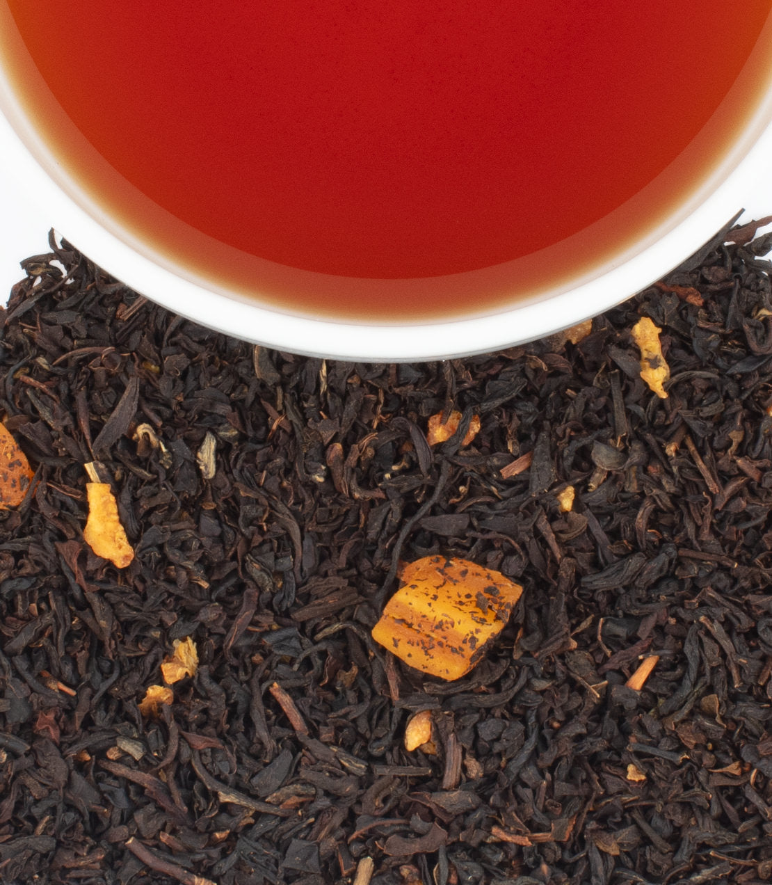 Harney & Sons Fine Teas- The Library Blend- Cup shot from above showing reddish brown tea in a cup surrounded by tea leaves with visible pieces of fruit