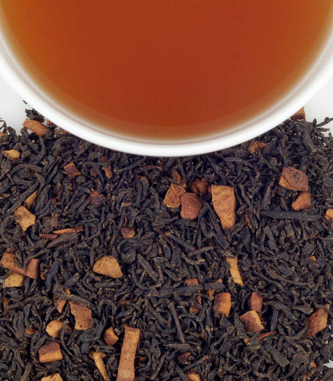 Hot Cinnamon Sunset tea sachets in a tin, with loose tea leaves and a cup of brewed tea above.