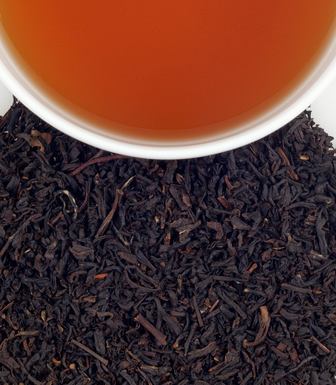 Classic tin of 20 sachets of Paris tea, with a cup of brewed tea and loose black tea leaves.