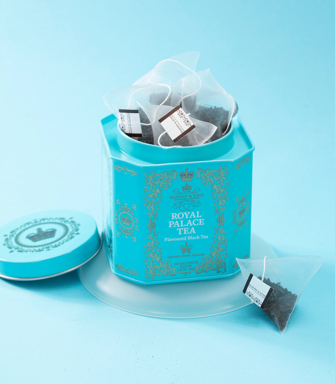 Blue tin of Royal Palace Tea with tea sachets on a light blue background.