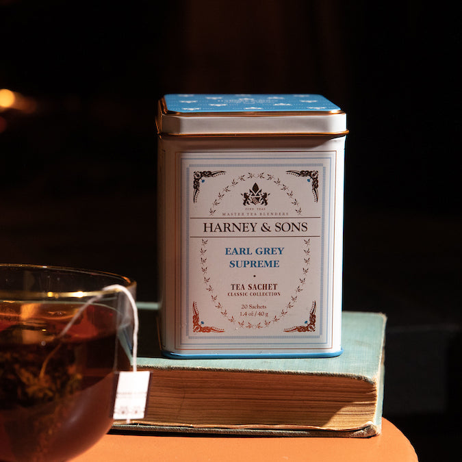 Earl Grey Supreme tea tin by Harney and Sons, featuring a classic design, placed beside a cup of brewed tea.
