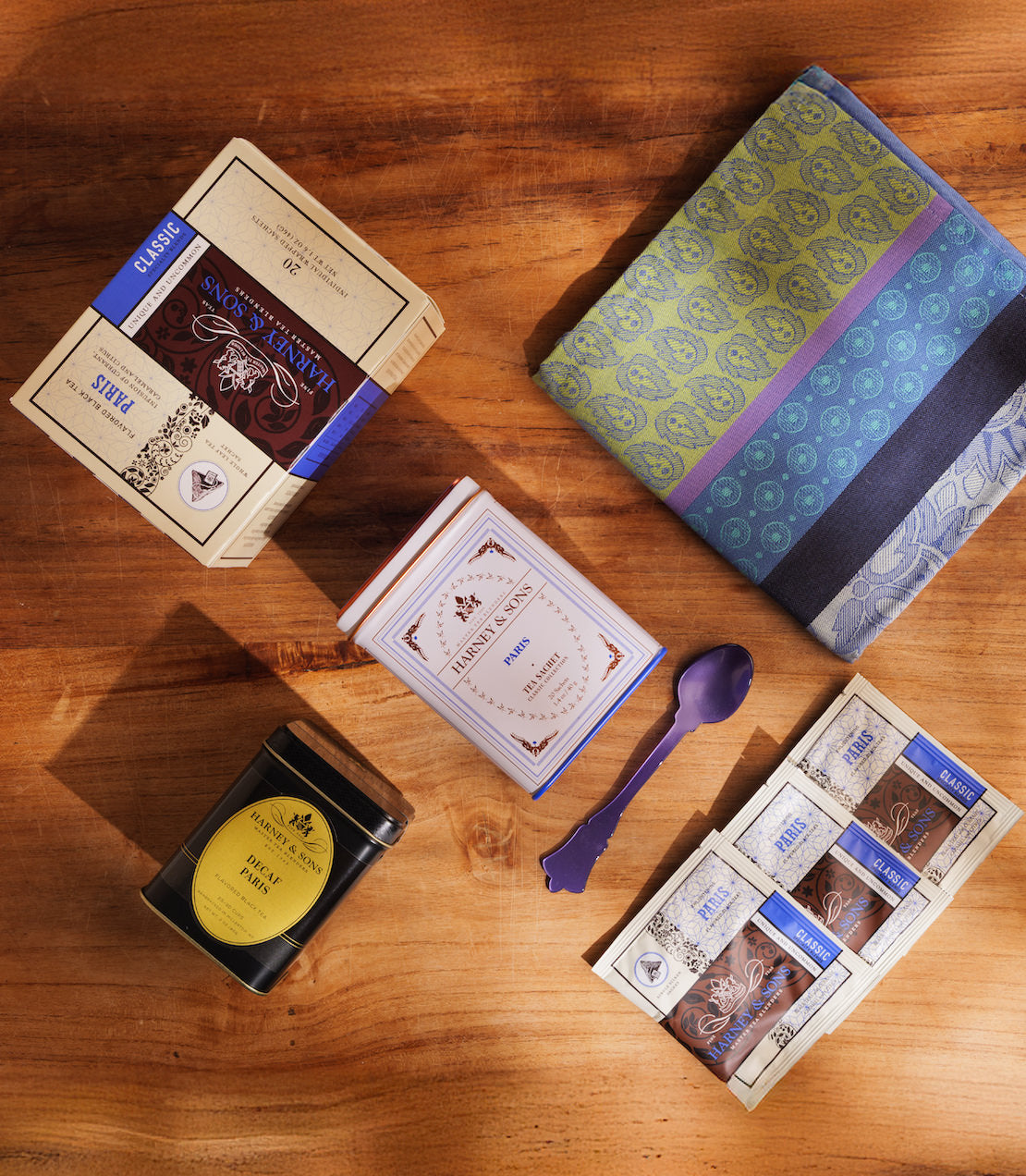 Assorted Paris tea packaging types with a tea towel on a wooden surface.
