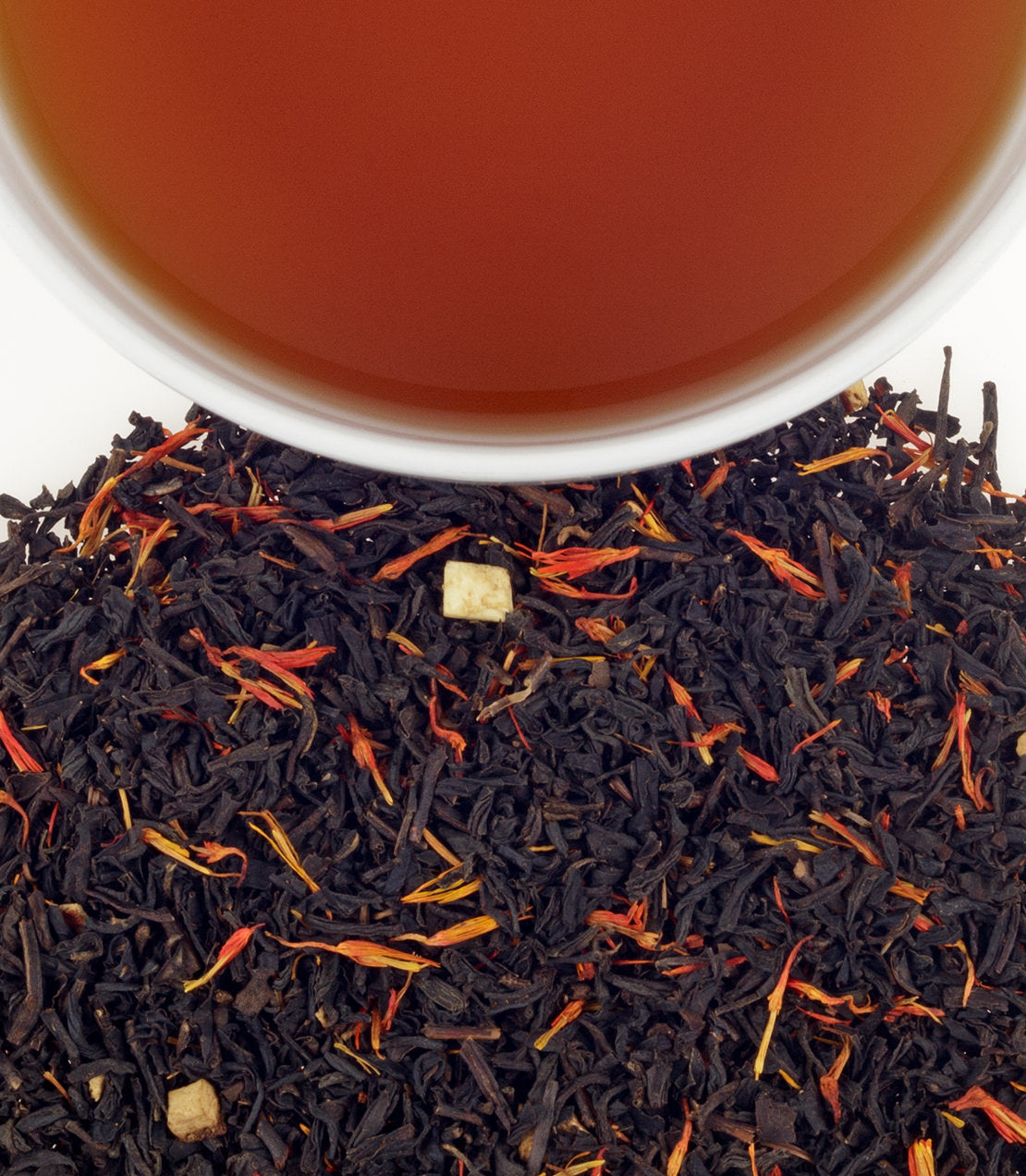 Holiday tea sachets in a tin, with loose tea leaves and a cup of brewed tea above.